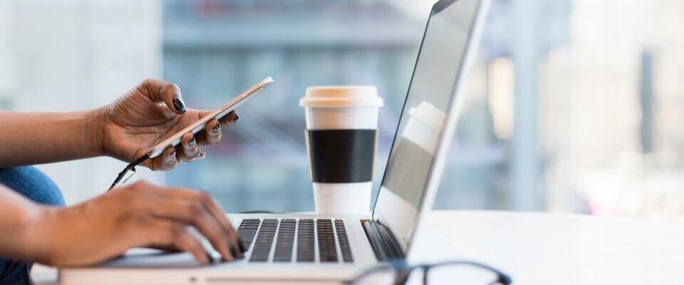 mulher usando notebook e smatphone ao mesmo tempo