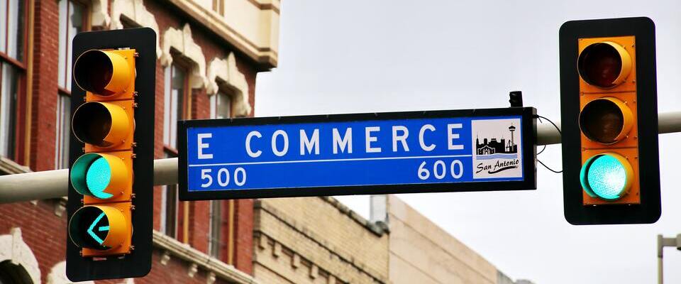 Placa azul entre semáforos com “e-commerce” escrito nela