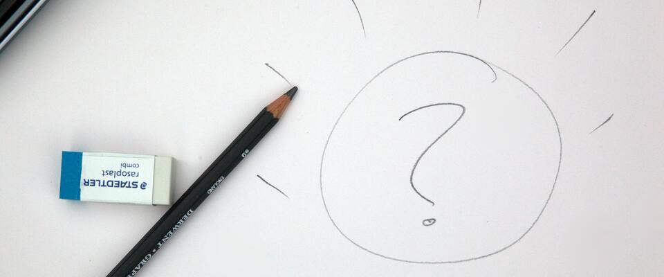 Desenho de uma lâmpada com uma interrogação no meio em folha de papel. Ao lado, lápis e borracha. 