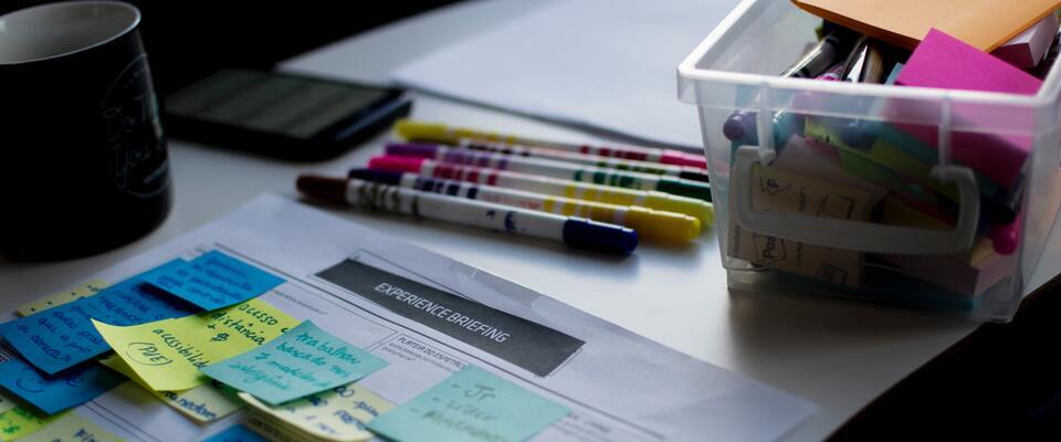 Folha com post-its colados e materiais de papelaria em volta.