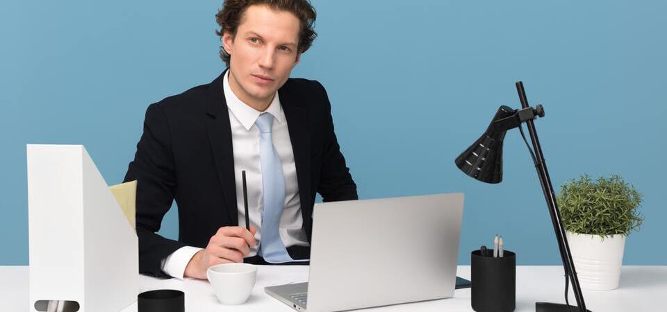 Homem usando terno e gravata em escritório minimalista.