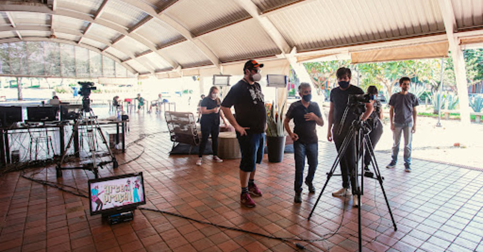 Gravação do arte na praça, com pessoas em frente ao palco observando a filmagem 