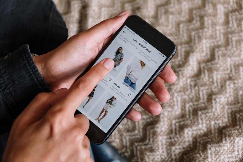 Pessoa usando celular para navegar por catálogo de produtos em um e-commerce.