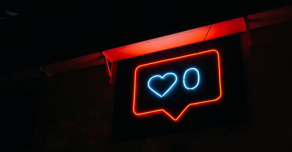 Placa neon com sinal de notificação de like do Instagram. O número de likes é zero.
