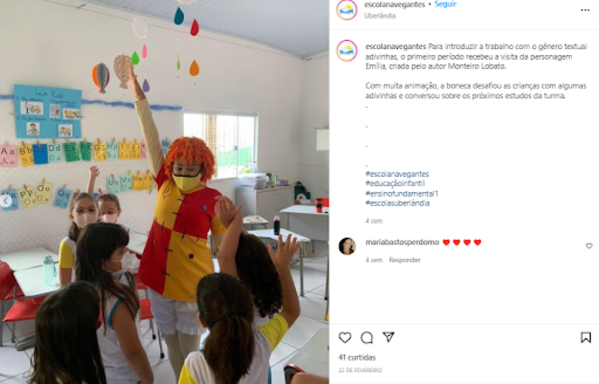 Captura de tela de um post do Instagram da Escola Navegantes, com uma professora fantasiada de Emília rodeada de crianças. 