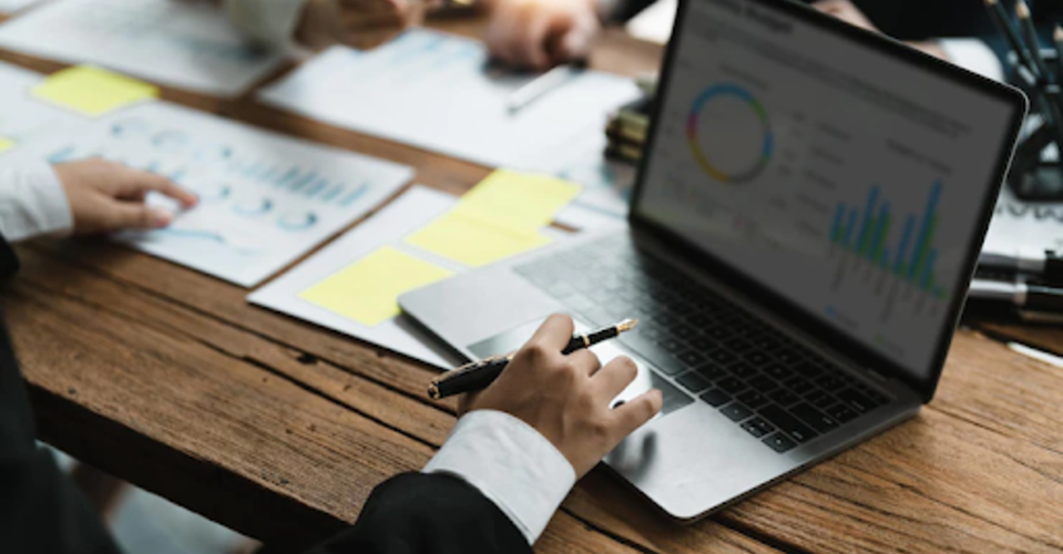 Reunião empresarial de planejamento de estratégias com computadores, métricas e papéis.