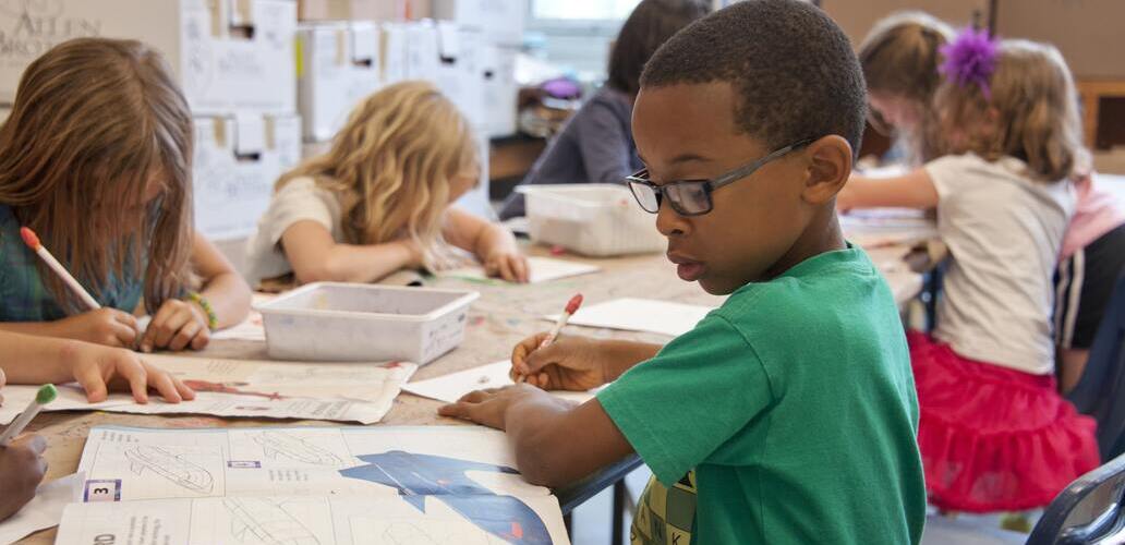 Crianças estudando com o auxílio de livros em sala de aula